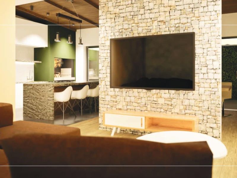 Modern open-plan living area featuring a stone feature wall, exposed timber ceiling beams, and a contemporary kitchen with a central island.