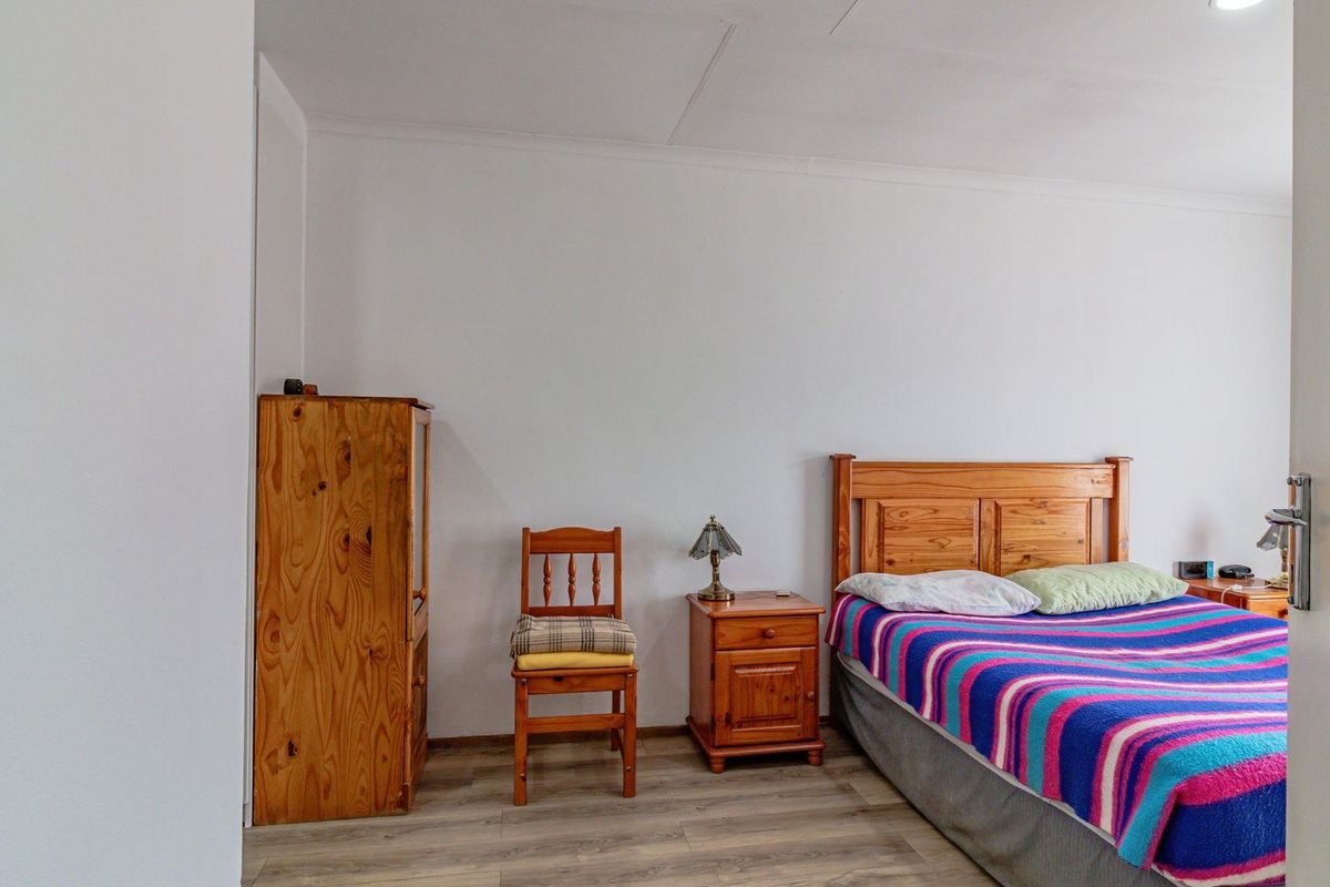 A bedroom featuring wood-look laminate flooring and neutral walls, providing a functional and well-lit space.