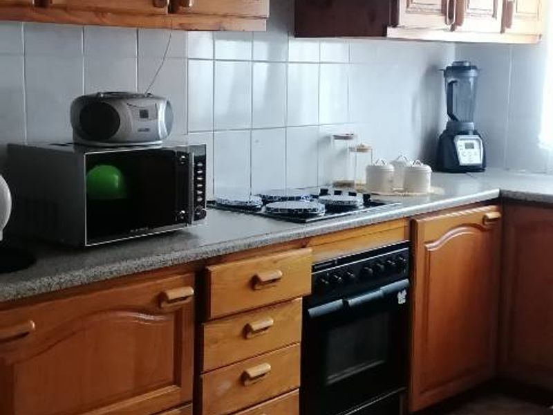 A functional kitchen featuring traditional wooden cabinetry, tiled backsplash, built-in oven, and gas hob with an extractor fan.