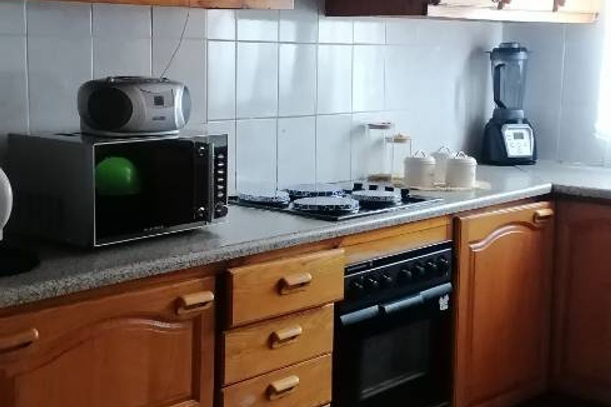 A functional kitchen featuring traditional wooden cabinetry, tiled backsplash, built-in oven, and gas hob with an extractor fan.