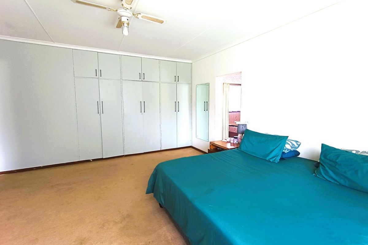 Spacious bedroom featuring extensive built-in cabinetry, neutral walls, and a ceiling fan, offering ample storage and a functional layout.