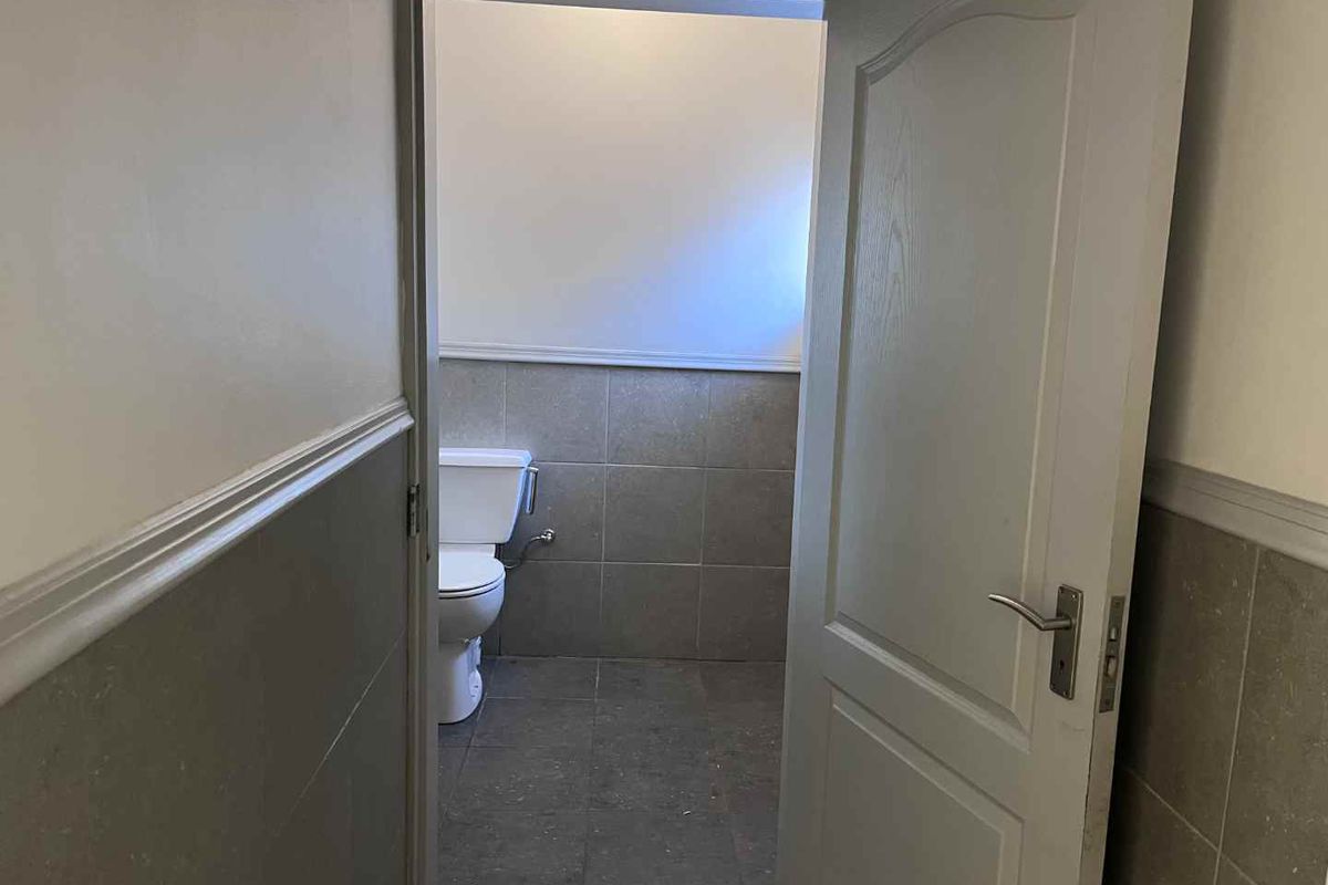 A functional bathroom featuring tiled walls and flooring, accessible via a standard interior door.