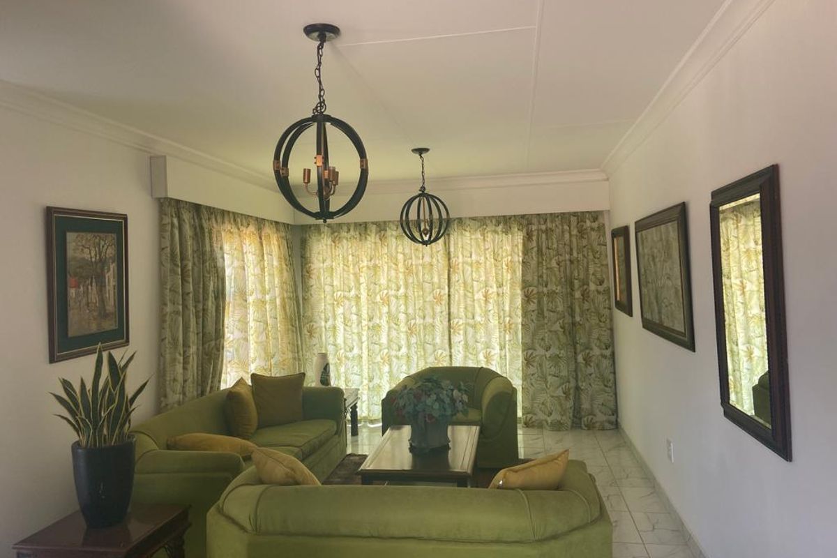 A comfortable living room featuring tiled flooring, decorative pendant lighting, and large floor-to-ceiling curtains covering the window wall.