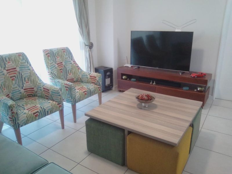 A living room area featuring tiled flooring and a large window, providing natural light to the space.