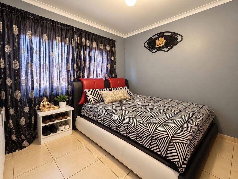 A bedroom featuring neutral tiled flooring and decorative cove cornicing, providing a functional space with a standard layout.