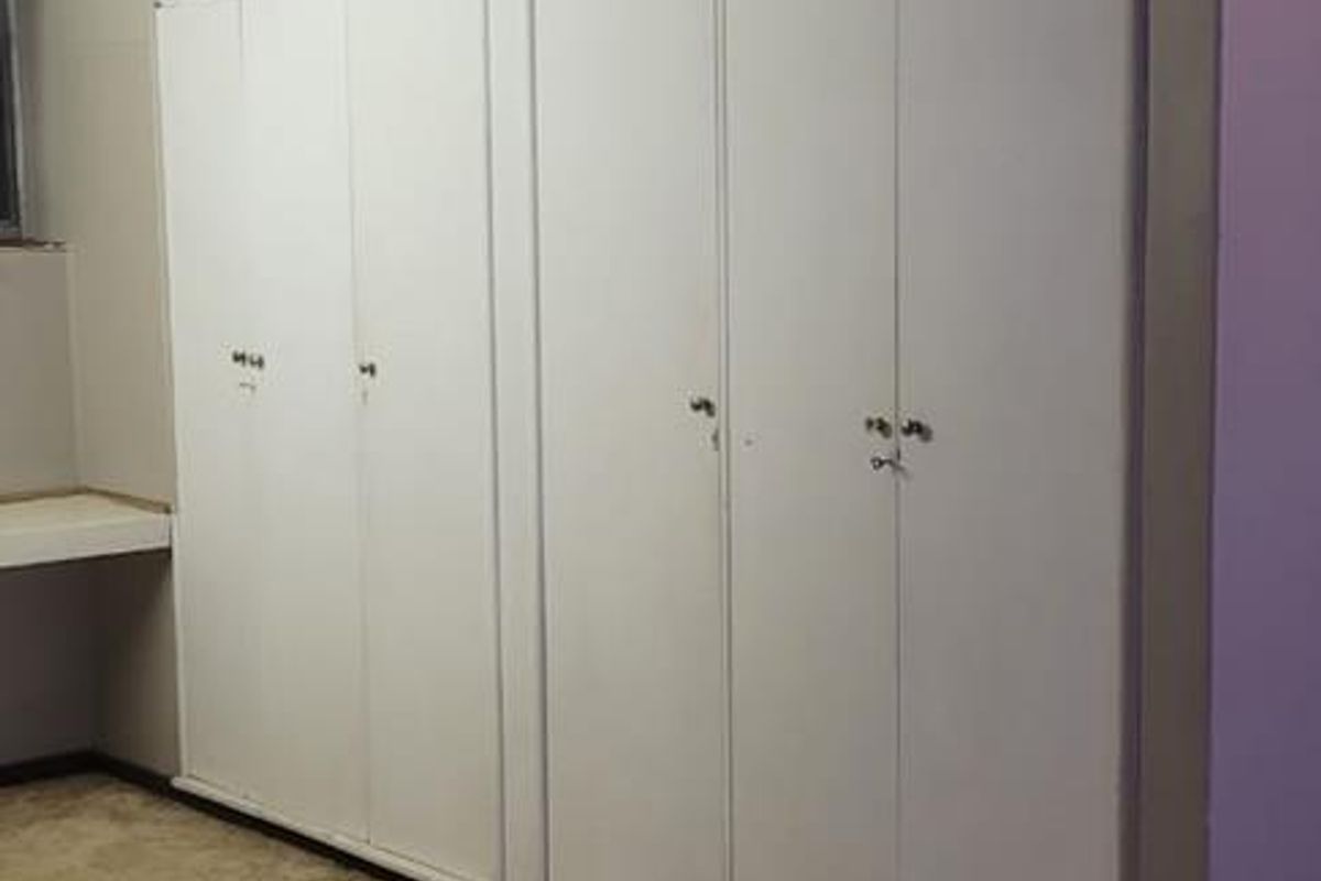 A bedroom featuring extensive floor-to-ceiling built-in cupboards and a fitted desk area, finished with carpeted flooring and coved ceilings.