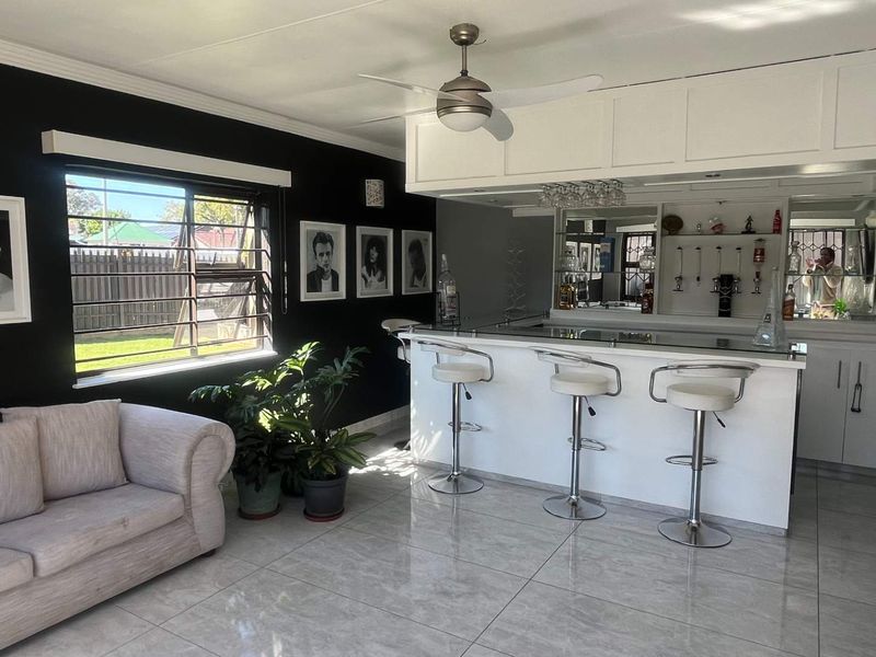 A well-appointed home bar area featuring a built-in counter, mirrored shelving, tiled flooring, and a ceiling fan, creating a dedicated space for entertainment.