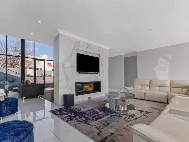 Modern living room featuring a striking marble-clad fireplace wall, large floor-to-ceiling windows, and polished tiled flooring, creating a bright and contemporary atmosphere.