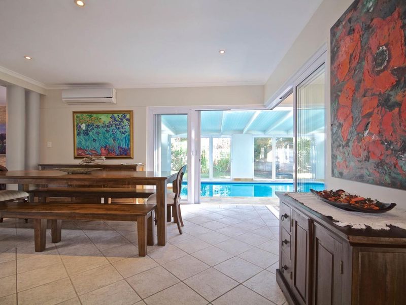 Spacious living area featuring tiled flooring, recessed lighting, and large sliding glass doors that provide seamless access to the outdoor pool area.