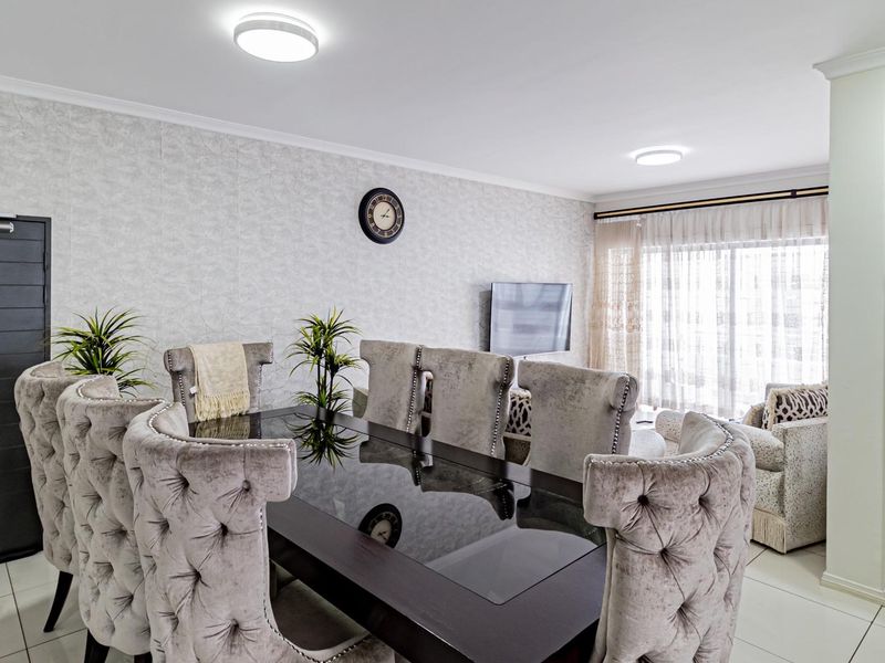 An open-plan living and dining area featuring tiled flooring, textured wallpaper, and modern recessed ceiling lighting with access to a balcony.