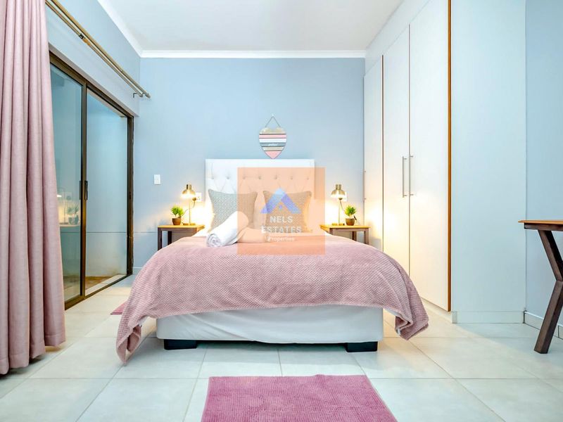 A well-maintained bedroom featuring built-in cupboards, tiled flooring, and a large sliding glass door providing access to the exterior.