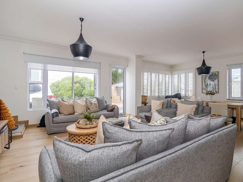 Spacious open-plan living and dining area featuring light hardwood flooring, modern pendant lighting, and plantation shutters, creating a bright and inviting atmosphere.