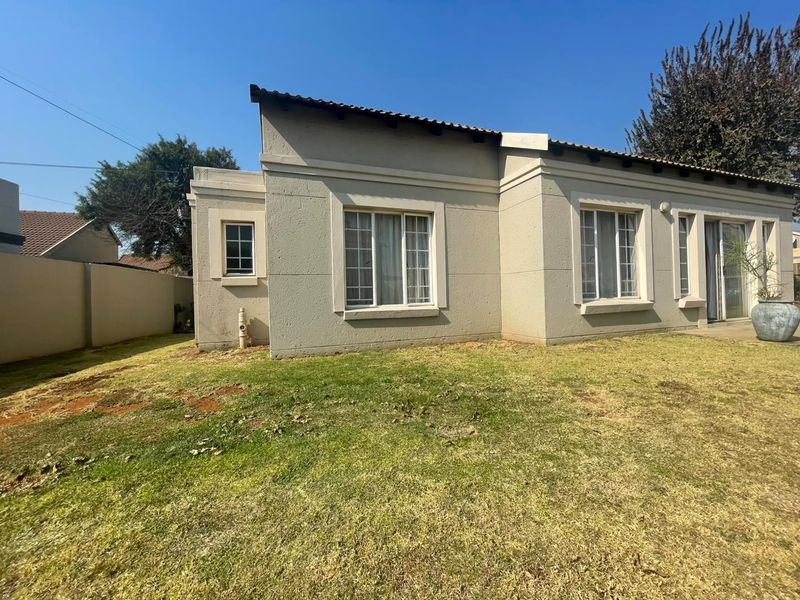 Rear view of the house featuring plastered walls, tiled roof, and sliding glass doors opening onto a lawn area.