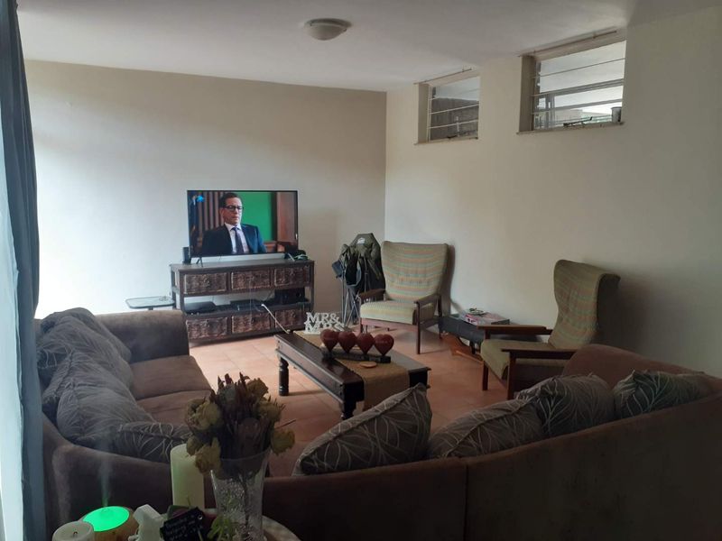 A comfortable living room featuring tiled flooring and high-set louvre windows, providing a functional and lived-in space.