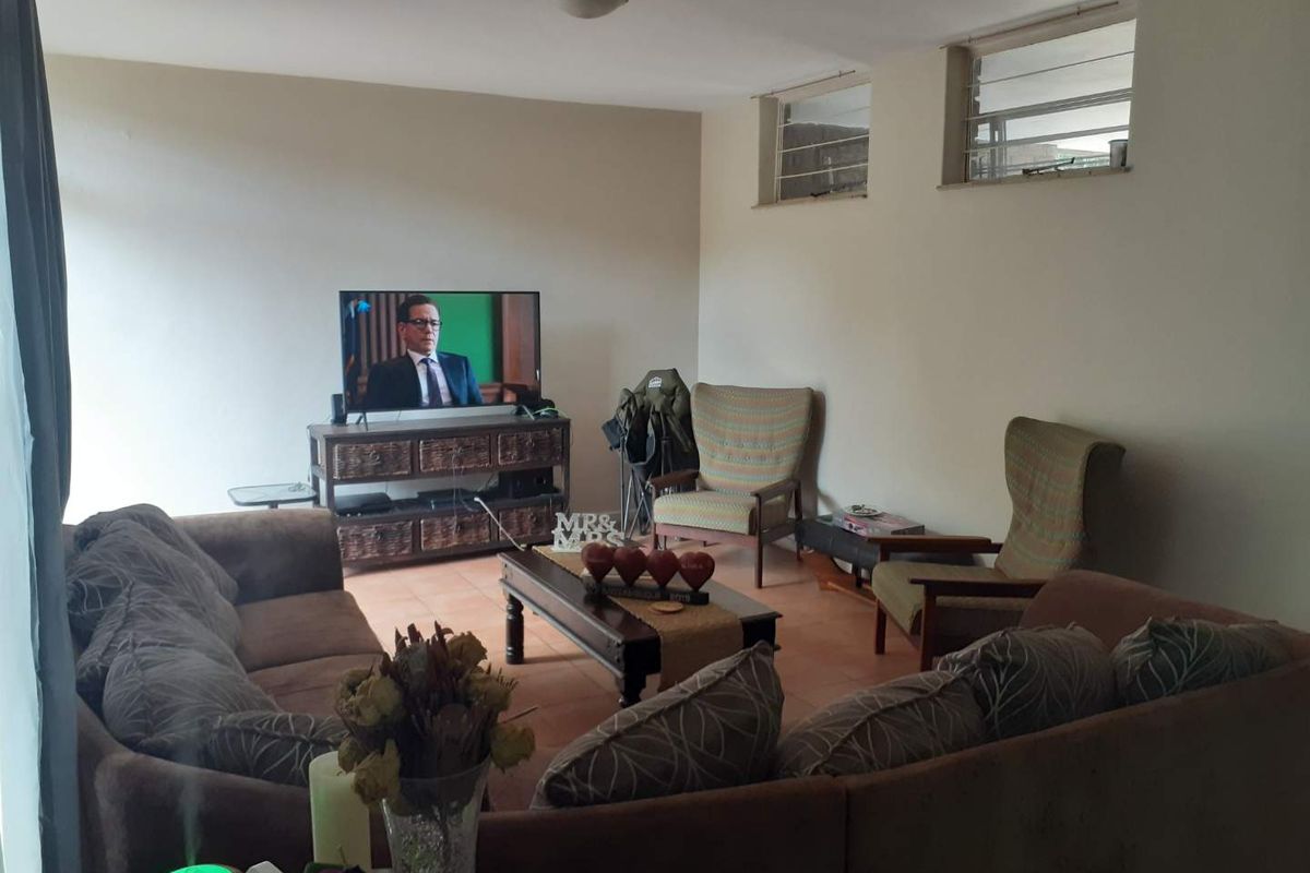 A comfortable living room featuring tiled flooring and high-set louvre windows, providing a functional and lived-in space.