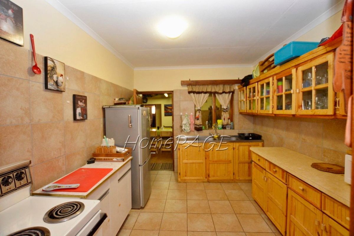 A functional kitchen featuring wooden cabinetry, tiled flooring, and a tiled splashback, providing a traditional workspace with integrated storage and preparation areas.