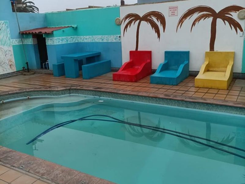 Outdoor pool area featuring a swimming pool with tiled surround and built-in concrete seating against a painted boundary wall.