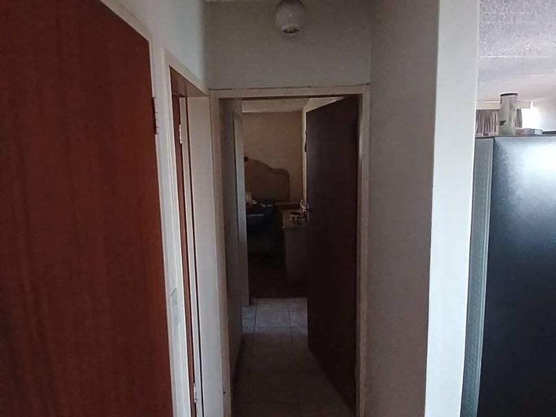 A functional hallway featuring tiled flooring and textured ceilings, providing access to adjacent rooms within the apartment.