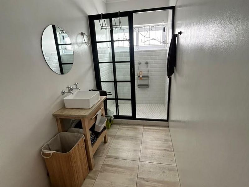 Modern bathroom featuring a vessel sink vanity, walk-in shower with black-framed glass enclosure, and subway tile wall finishes.