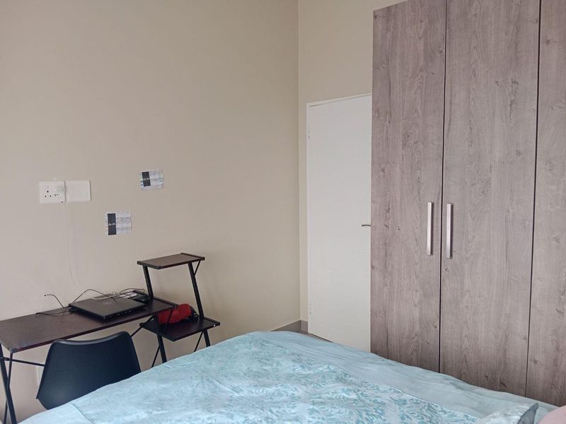 A bedroom featuring a modern wood-finish built-in wardrobe and neutral wall tones.