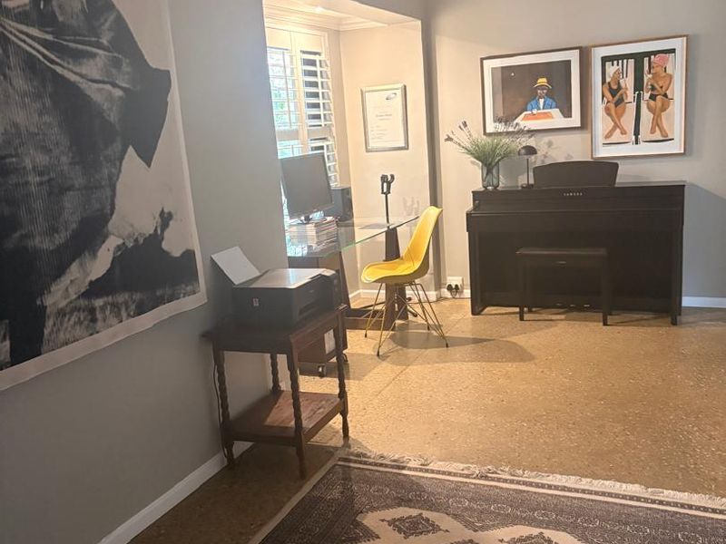A bright home office space featuring polished concrete floors, recessed lighting, and plantation shutters, providing a functional and well-maintained work area.