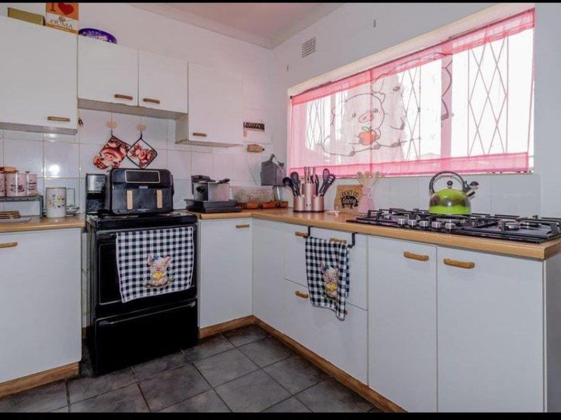 A functional kitchen featuring white cabinetry, wooden countertops, a gas hob, and tiled flooring, offering a practical layout for daily cooking.