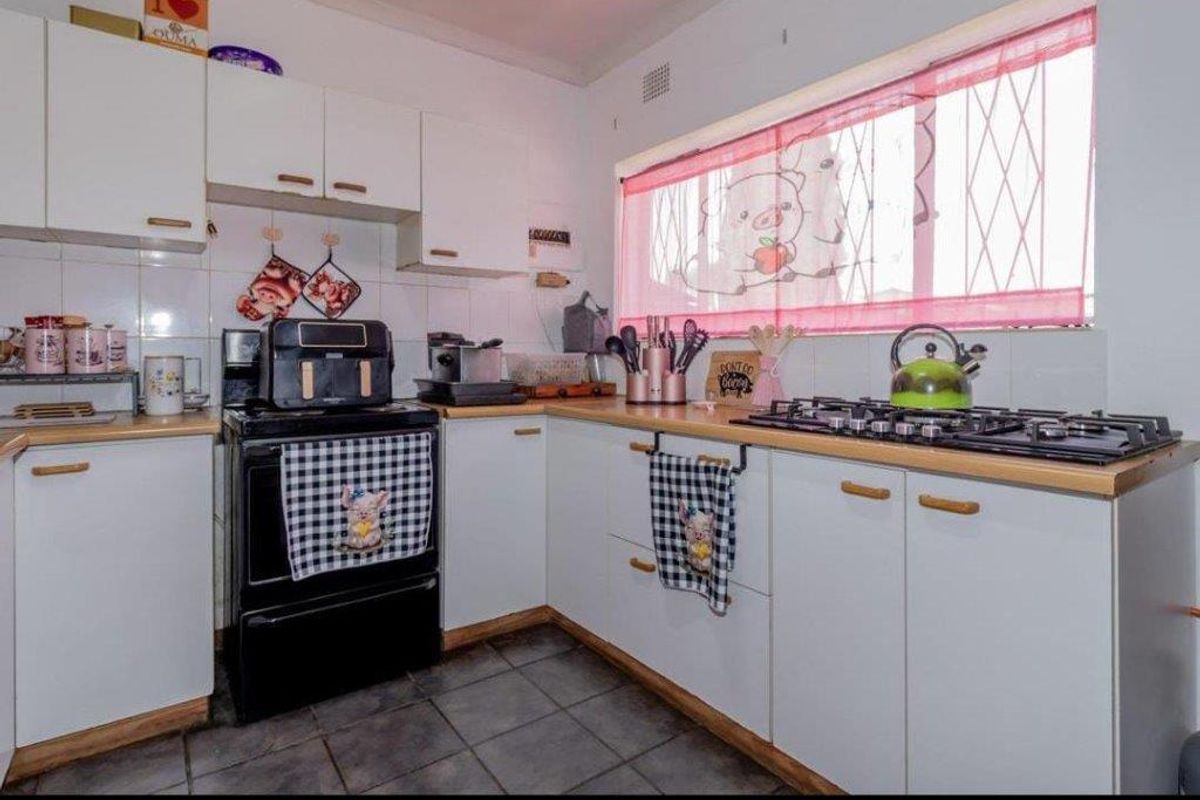 A functional kitchen featuring white cabinetry, wooden countertops, a gas hob, and tiled flooring, offering a practical layout for daily cooking.