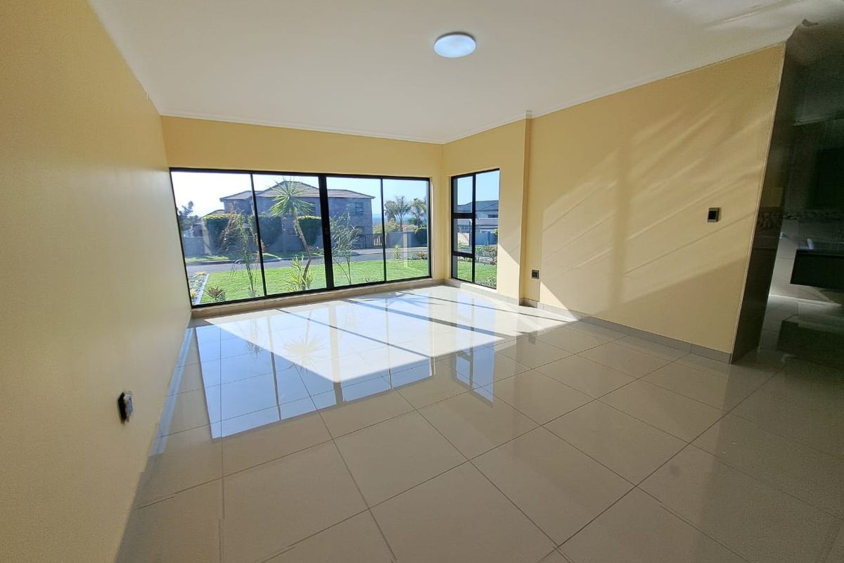 A bright, empty living room featuring large floor-to-ceiling windows, polished porcelain floor tiles, and neutral wall finishes.