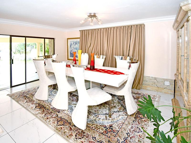 A bright dining room featuring tiled floors, crown molding, a stone veneer accent wall, and large sliding glass doors leading to an outdoor area.