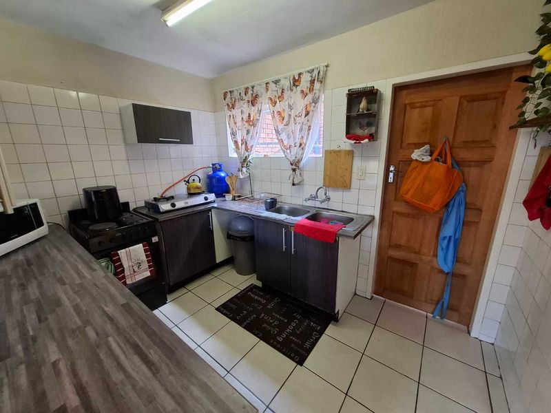 A functional kitchen featuring tiled splashbacks, double basin sink, and built-in cabinetry with laminate countertops.