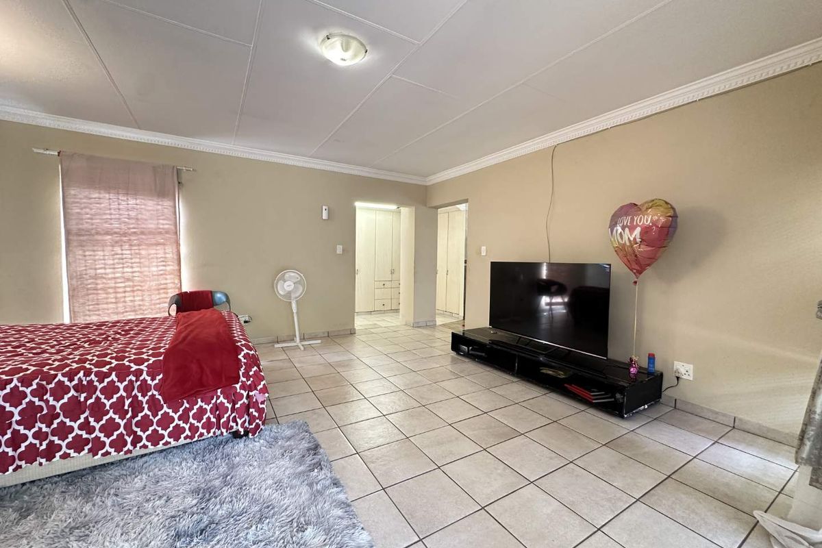 Spacious bedroom featuring tiled flooring, crown molding, and direct access to a built-in wardrobe area.