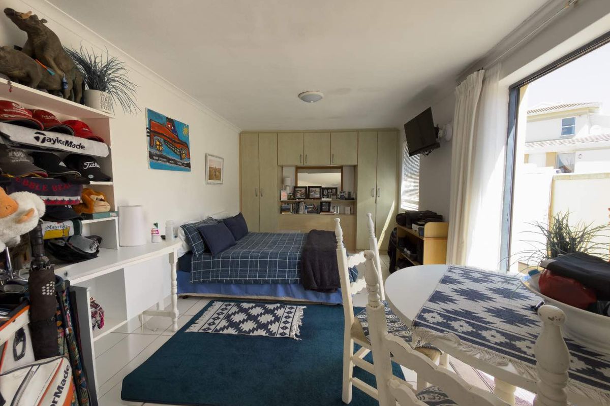 A bedroom featuring built-in cupboards, tiled flooring, and a sliding glass door providing access to the exterior.