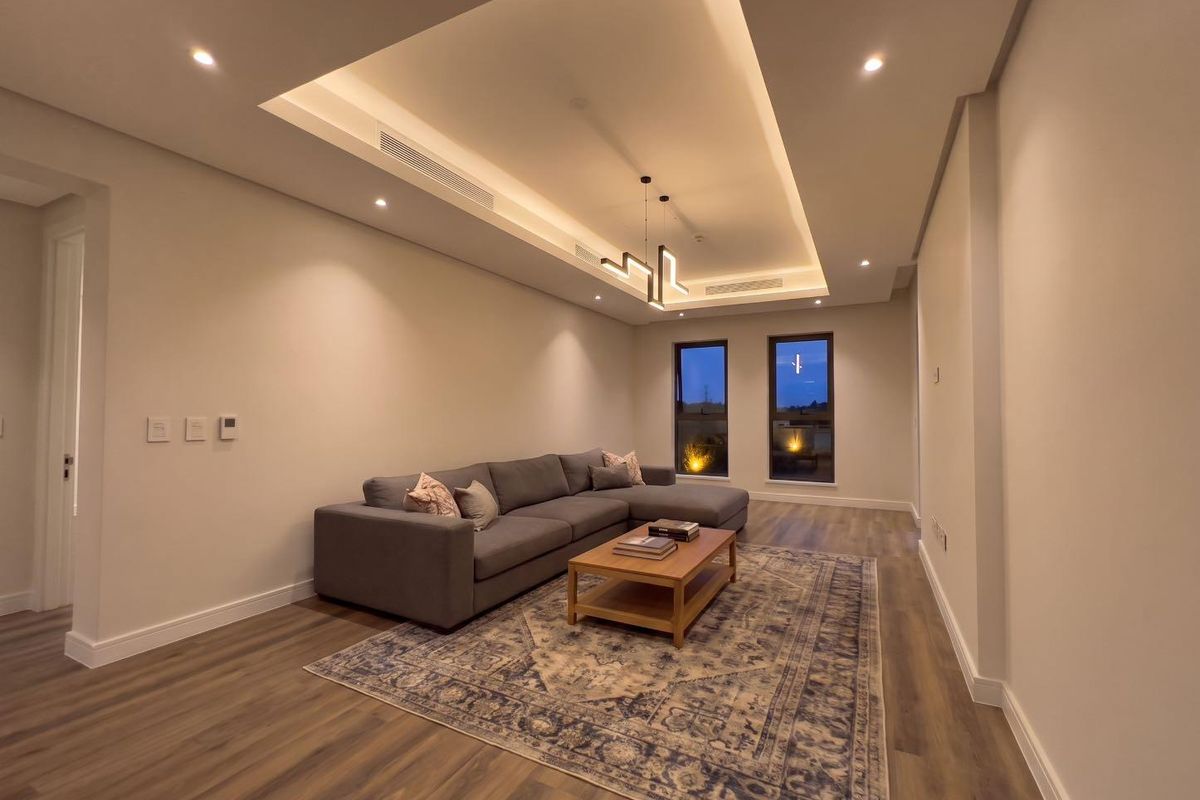 Modern living room featuring a recessed ceiling with integrated cove lighting, ducted air conditioning, and high-quality laminate flooring.
