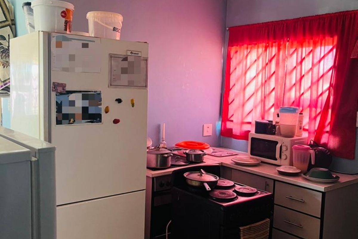 A compact kitchen featuring tiled flooring, built-in cabinetry, and a freestanding stove, currently requiring cosmetic updates to modernize the space.