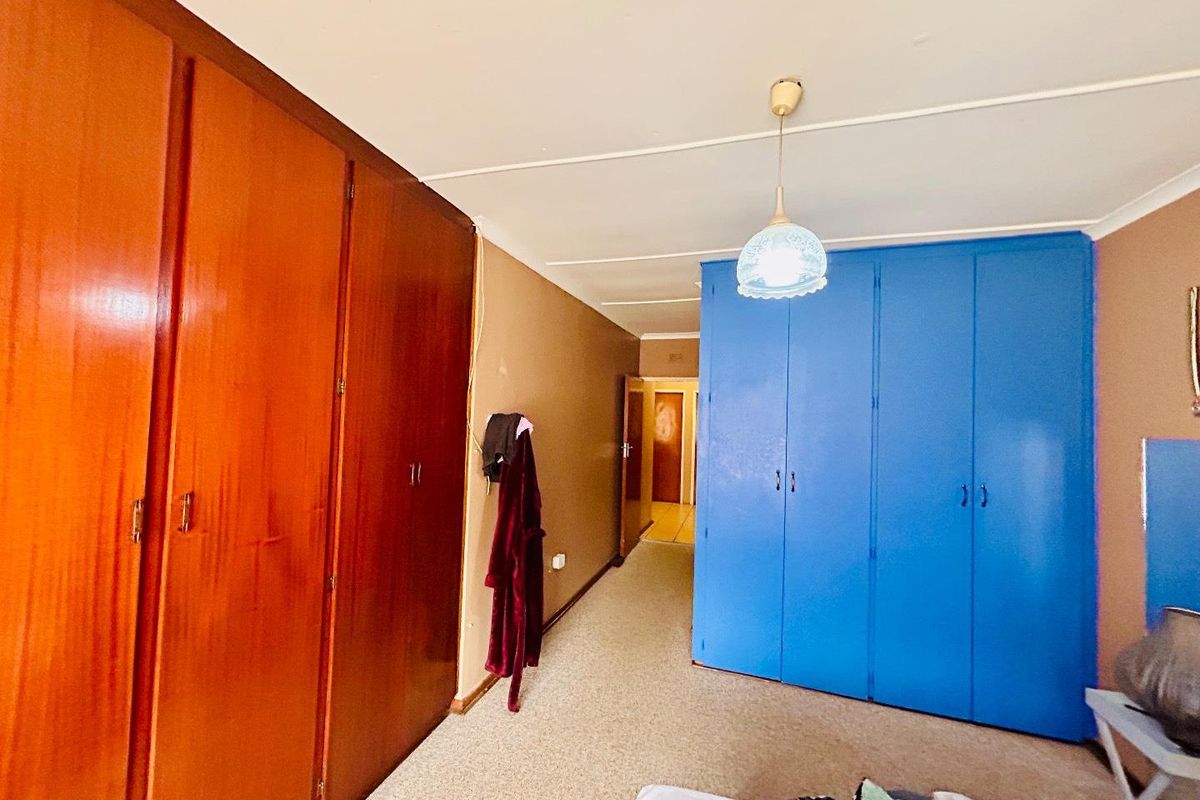 Bedroom featuring extensive built-in wooden and blue cabinetry, carpeted flooring, and a central pendant light fixture.