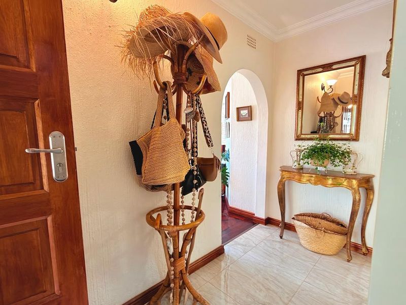 A welcoming entrance hall featuring tiled flooring, a decorative archway leading to the interior, and classic wall sconce lighting.