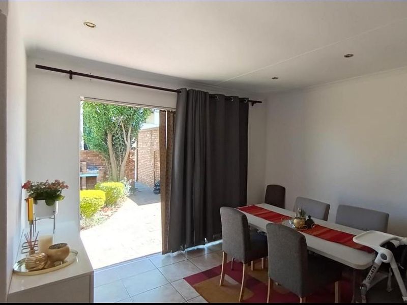 Dining area featuring tiled flooring and recessed downlights, with direct access to the rear garden through a sliding glass door.