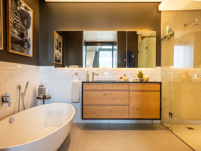 Modern bathroom featuring a sleek wall-mounted vanity, a freestanding bathtub, and a spacious walk-in shower with glass enclosure and contemporary finishes.