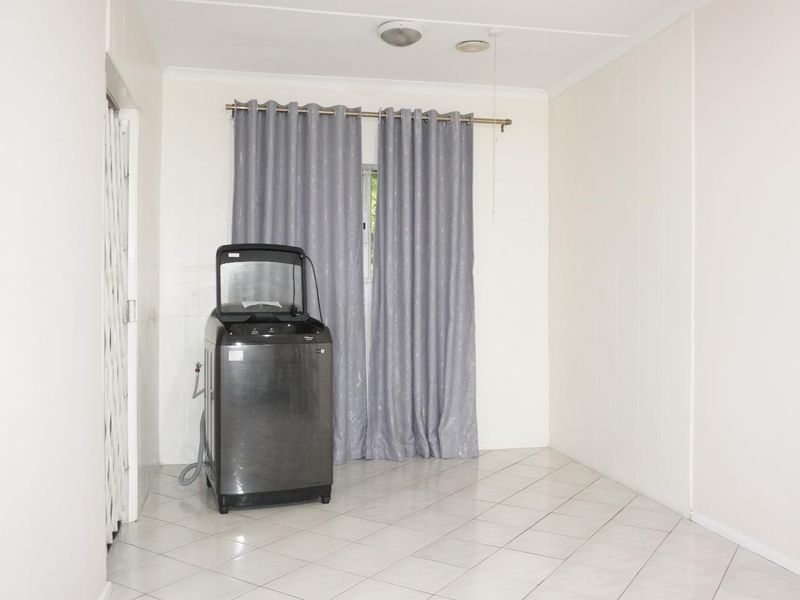 A functional laundry area featuring tiled flooring and a security gate, providing a clean and practical space for utility needs.