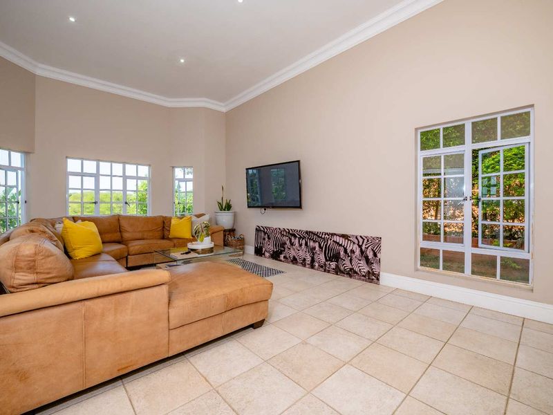 Spacious living room featuring neutral tiled flooring, recessed downlighting, and large casement windows providing ample natural light.