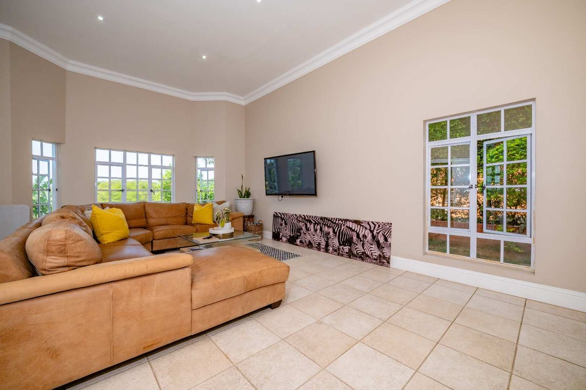 Spacious living room featuring neutral tiled flooring, recessed downlighting, and large casement windows providing ample natural light.