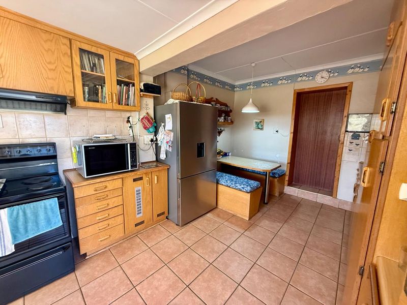 A functional kitchen featuring wooden cabinetry, tiled flooring, and a tiled backsplash, offering a traditional layout with integrated cooking appliances.