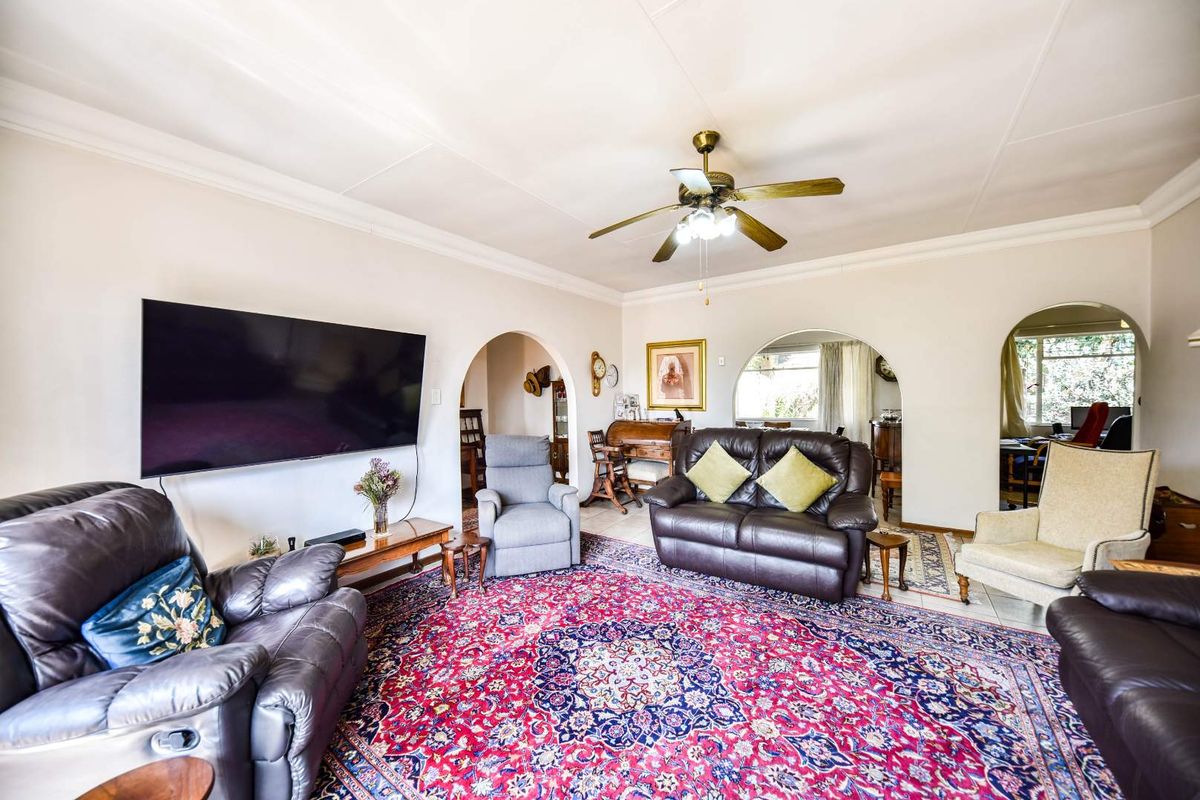 Spacious living room featuring classic archways, tiled flooring, and a central ceiling fan, providing a comfortable and traditional living space.