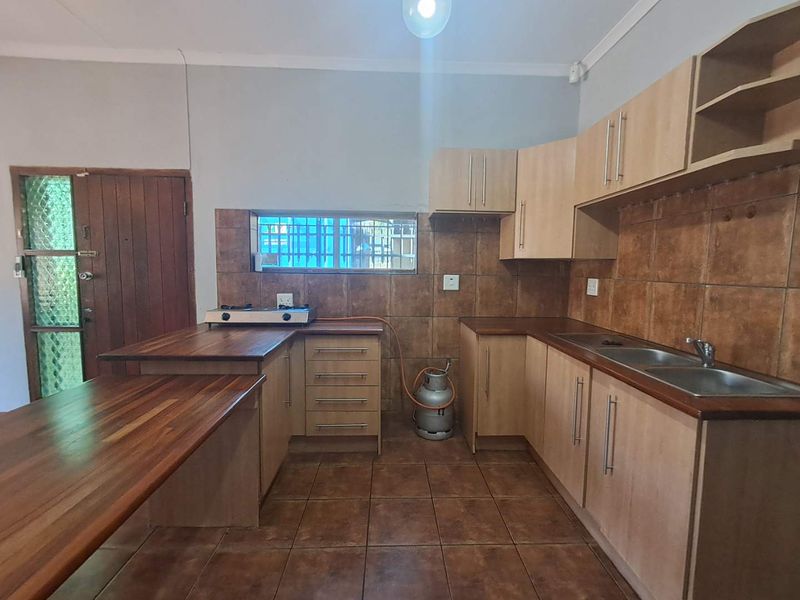 Functional kitchen featuring wooden countertops, laminate cabinetry, double basin sink, and tiled finishes, offering a practical layout for culinary activities.