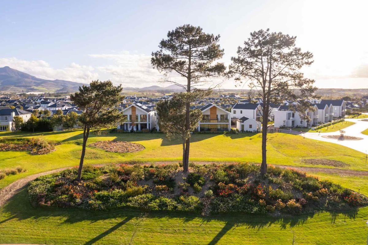 An aerial view of a well-maintained residential estate featuring landscaped gardens, mature trees, and modern housing units.
