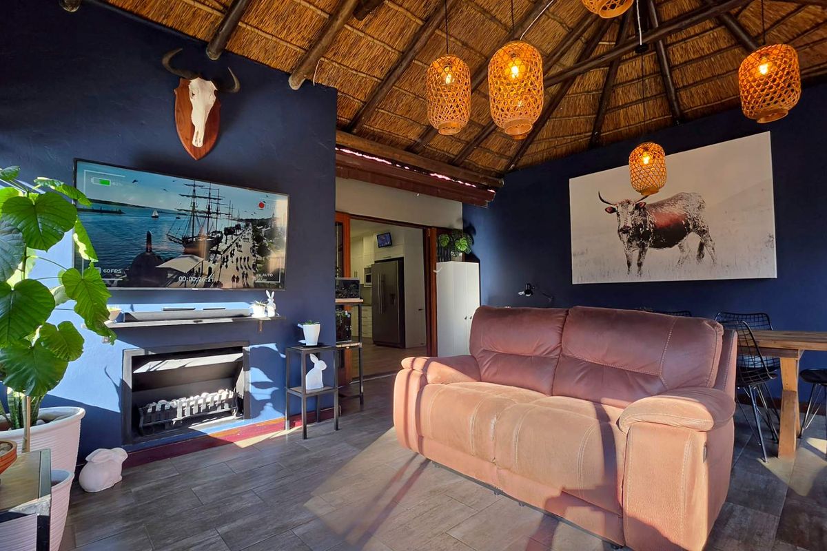 A cozy living room featuring a traditional thatched roof, a built-in fireplace, and dark blue accent walls, creating a warm and inviting atmosphere.