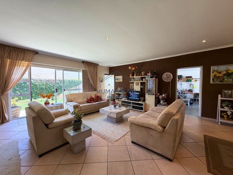 Spacious living room featuring tiled flooring, recessed downlighting, and large sliding glass doors providing direct access to the outdoor area.