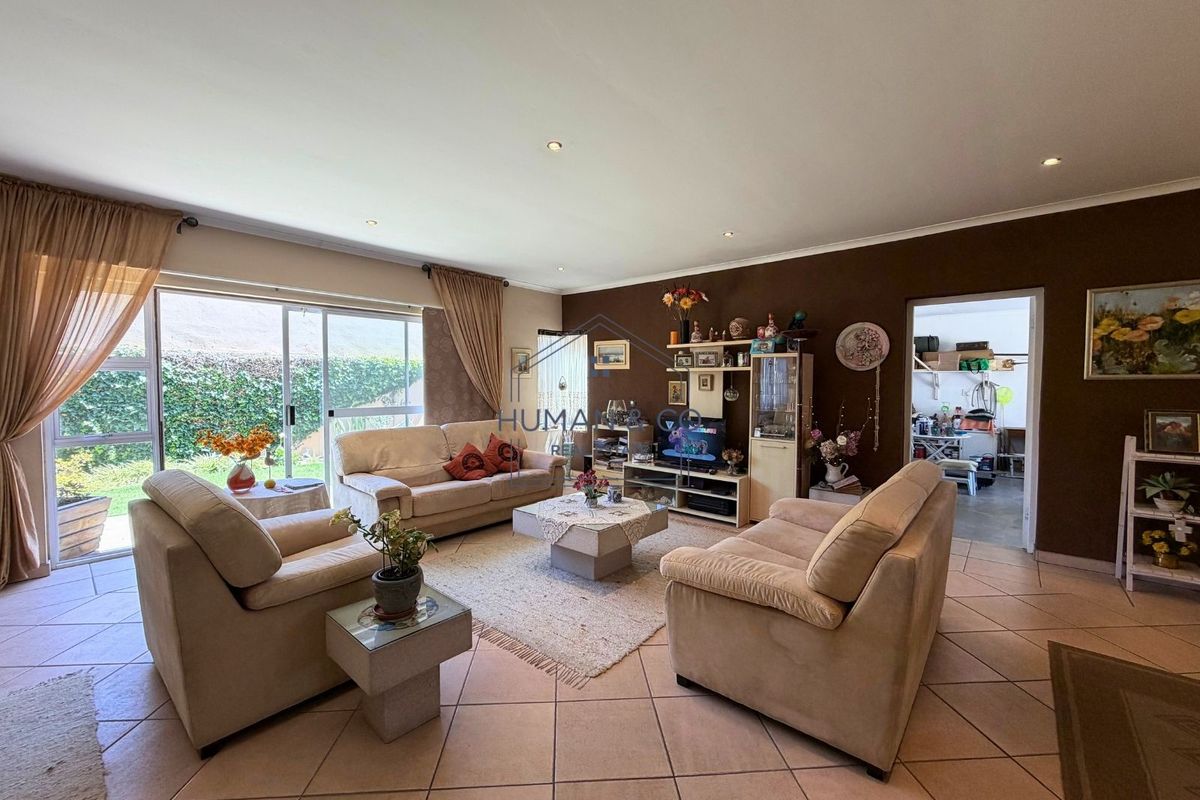 Spacious living room featuring tiled flooring, recessed downlighting, and large sliding glass doors providing direct access to the outdoor area.