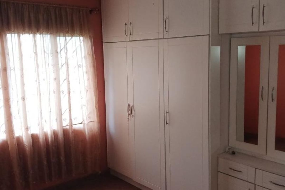 A bedroom featuring extensive built-in cupboards, a built-in vanity unit, and tiled flooring, offering ample storage space.