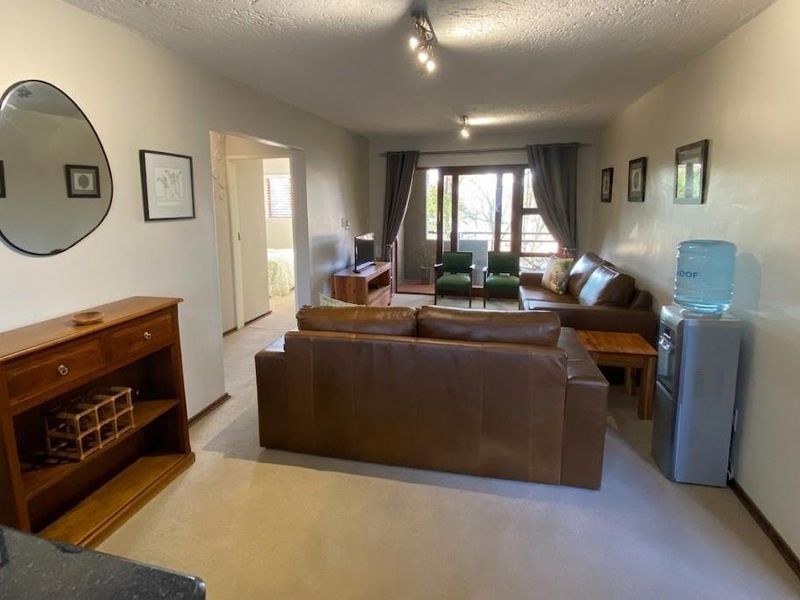 Spacious living room featuring neutral carpeting, ceiling track lighting, and a sliding glass door providing access to an outdoor balcony area.